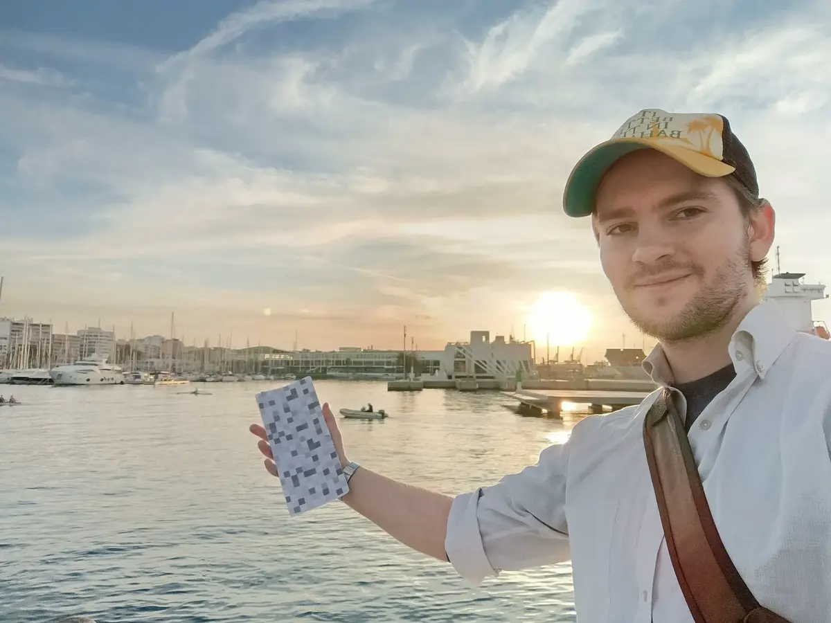 Magnus holding a project card beside a waterfront