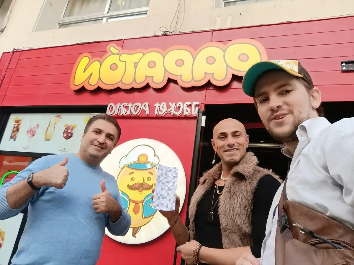 Magnus and two people sharing the project card outside a restaurant